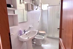 a white bathroom with a toilet and a sink at Blue apartment, Alghero, near beaches in Alghero