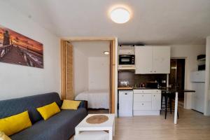 a living room with a couch and a kitchen at Residence du Centre Joli studio rénové avec coin nuit terrasse et parking privé in Capbreton