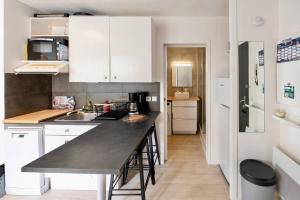 a kitchen with white cabinets and a black counter top at Residence du Centre Joli studio rénové avec coin nuit terrasse et parking privé in Capbreton +1 photo