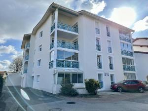 a white building with a car parked in front of it at Residence du Centre Joli studio rénové avec coin nuit terrasse et parking privé in Capbreton