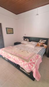 a bedroom with a large bed with a pink blanket at Jungfra farmstay in Pulpally