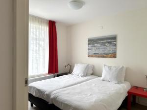 two beds in a bedroom with a red window at Huis van Egmond aan Zee in Egmond aan Zee