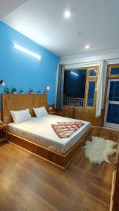 a bedroom with a large bed with a blue wall at Diya Mountain House Tirthan in Banjār