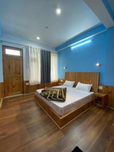 a bedroom with a large bed with blue walls and wooden floors at Diya Mountain House Tirthan in Banjār
