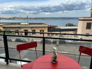 a red table and chairs on a balcony with a view at Acqua Holiday House in Taranto