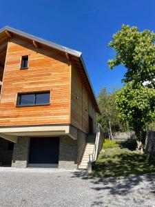 a wooden building with a garage and a tree at le chalet de st Anne in Jausiers