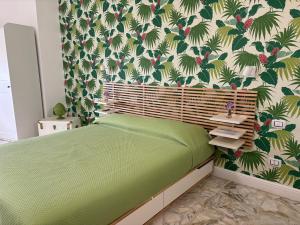 a bedroom with a green bed with a tropical wallpaper at Acqua Holiday House in Taranto