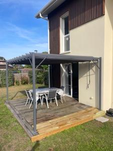 un patio avec une table et des chaises sur une terrasse dans l'établissement Douceur Atlantique, à Mimizan