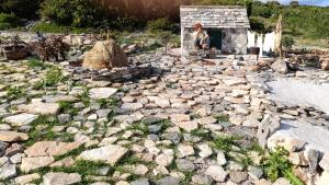 a person sitting on a rocky ground with a building at Vila Ivana Dolores in Vinišće