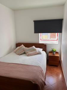 Un dormitorio con una cama con dos almohadas y una ventana. en Ninho da Praia, en Baleal