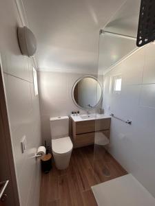 Un baño blanco con inodoro y espejo. en Ninho da Praia, en Baleal 11 fotos más