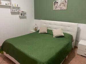 a bedroom with a green bed with a white headboard at Villetta SCHIRÒ - BAGNASCO in Campofelice di Roccella +22 photos