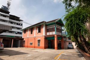 a large orange building with a car parked in a parking lot at Au samlor guesthouse in Chinatown
