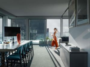 a woman walking in a kitchen with a table and chairs at The Olsen Melbourne Art Series in Melbourne
