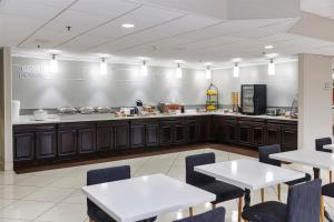 un ristorante con tavoli e bancone con cucina di Elimwood Hotel, a Ramada by Wyndham a Maryland Heights