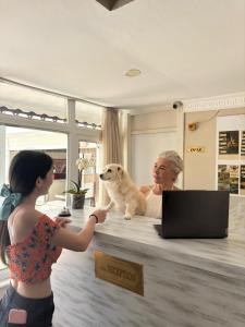 a woman with a dog sitting at a reception desk at MOY Beldibi Hotel in Antalya