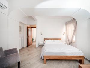 a white bedroom with a bed and a chair at The Sun by alle Stelle b&b in Anacapri