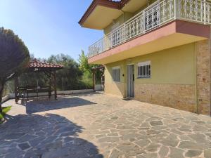 a balcony on the side of a building with a patio at Elena's 3BR Maisonette with Garden & Pool in Nea Plagia
