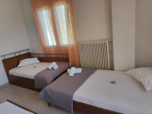 two beds in a hotel room with towels on them at Elena's 3BR Maisonette with Garden & Pool in Nea Plagia