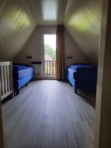 a attic room with two beds and a window at De Gouwe, 158 - aan visvijver, de beste visstek in Gramsbergen +25 photos