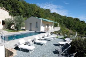 a swimming pool with white chairs next to a house at Le Cune, Apt Cipressino - AC, Pool & Jacuzzi in Palazzo