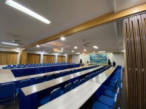 an empty lecture hall with blue chairs and a podium at Satya Graha Hotel in Timuran