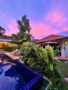 a villa with a swimming pool in front of a house at Beautiful garden 3 bedroom villa close to beach in Plai Laem