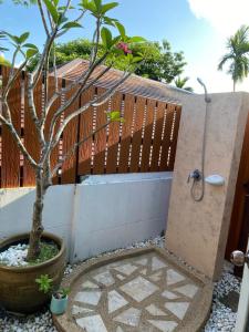 a shower in a fence with a potted tree at Beautiful garden 3 bedroom villa close to beach in Plai Laem