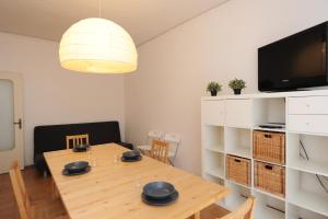 a dining room with a wooden table and a tv at Tizi Apartments Porto in Maiori