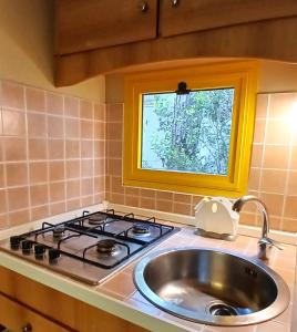 a kitchen with a sink and a stove and a window at Camping Village Il Sole in Marina di Grosseto