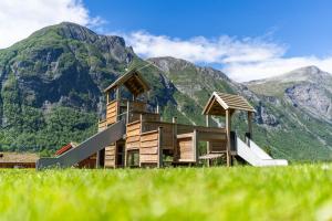 a house in a field with mountains in the background at Trollstigen Camping and Gjestegård in Åndalsnes