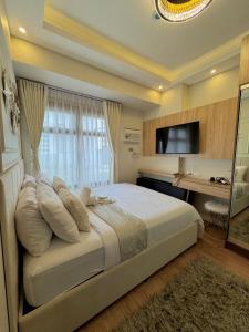 Schlafzimmer mit einem Bett, einem Schreibtisch und einem TV in der Unterkunft Manila Bay Suite near PICC in Manila