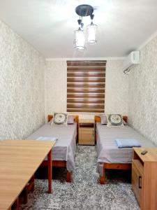 a room with two beds and a table and a window at Зухро in Bukhara
