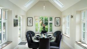 a dining room with a table and chairs and windows at Superb 4BD Stay in Wyton and Houghton Village in Wyton