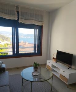 a living room with a tv and a glass table at Piso Beiramar in Pontevedra
