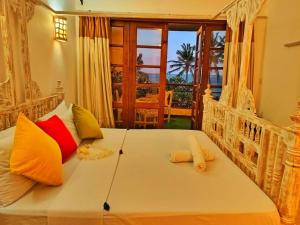 a bedroom with a white bed with colorful pillows at Shanzu Oceanline Apartments La Mera in Mombasa