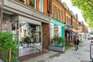 a woman walking down a street in front of stores at NEW Cosy 1BD Flat close to Kew Gardens Richmond in London