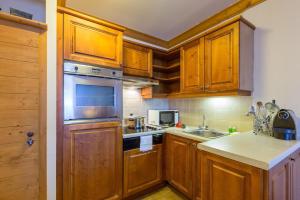 een keuken met houten kasten en een kookplaat met oven bij Résidence Les Sources de Marie - ARCS 1950 in Bourg-Saint-Maurice