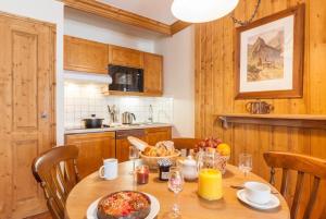 een keuken met een houten tafel met eten erop bij Résidence Les Sources de Marie - ARCS 1950 in Bourg-Saint-Maurice