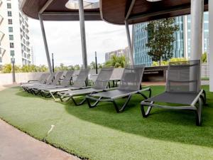 a row of chaise lounge chairs sitting on grass at Encorp Marina Puteri Harbour 2Bed Bathtub in Iskandar Puteri