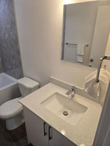 a bathroom with a sink and a toilet and a mirror at Cozy 2-Bedroom Suite 5 Minutes Walk to Chestermere Lake in Chestermere +10 photos
