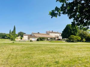 a large grass field with a house in the background at Gites le Fabras, espace de verdure, piscine collective et jeux in La Bâtie-Rolland
