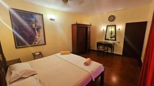 a bedroom with a bed and a desk in it at Raintree Lodge in Cochin