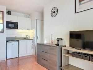 una cucina con armadi bianchi e un orologio sul muro di Le Thalio - Swimming pool - Air conditioning a Gruissan