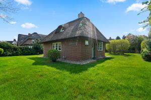 a small brick house in a grassy yard at Kampens Herzstück in Kampen
