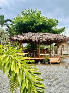 a hut with a bench and a straw roof at La Casita Feliz in Puerto Princesa City
