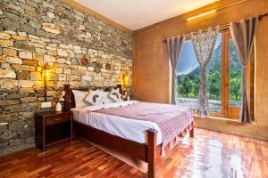 a bedroom with a bed and a stone wall at Himalayan Willow in Gushaini