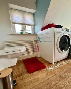 a washing machine in a bathroom with a red rug at Kleine Landhaus-Perle am Schlosspark in Eutin +39 photos