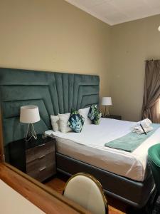 a bedroom with a large bed with a green headboard at St Eve Lodge & Spa in Bloemfontein +37 photos