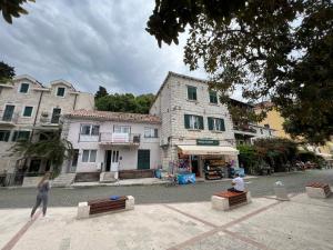 two people sitting on benches in front of a building at Apartments Astoria HN in Herceg-Novi